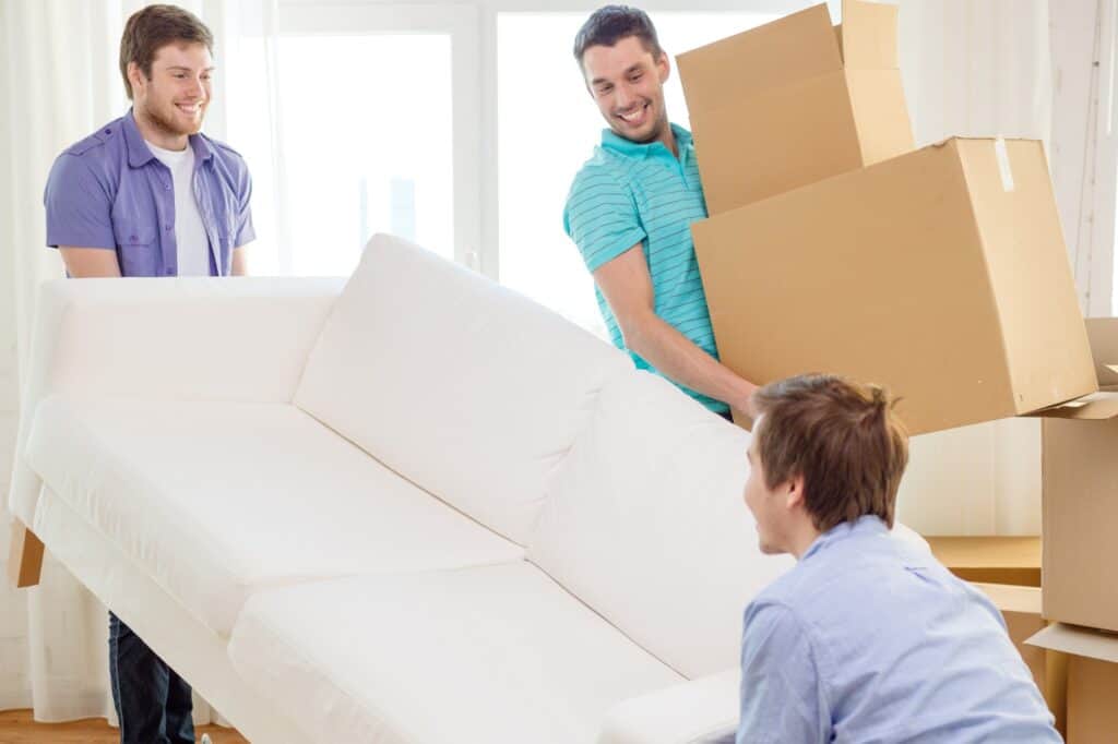 Friends in their new apartment with sofa and boxes in the concept of moving to Barnet
