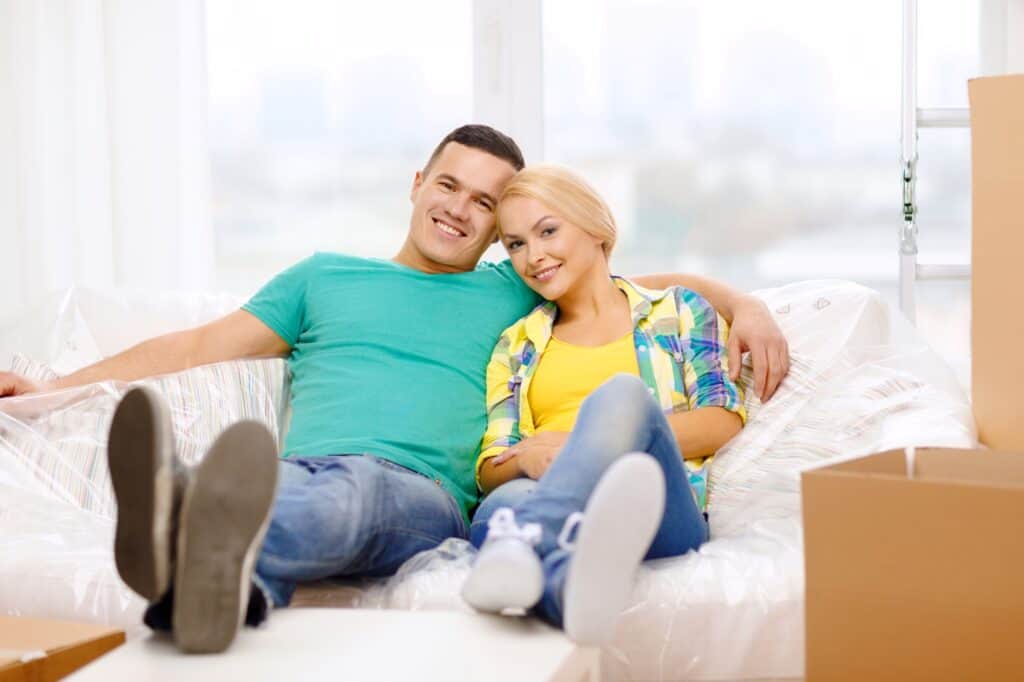 A couple is sitting on their wrapped sofa in the concept of moving to Barnet.