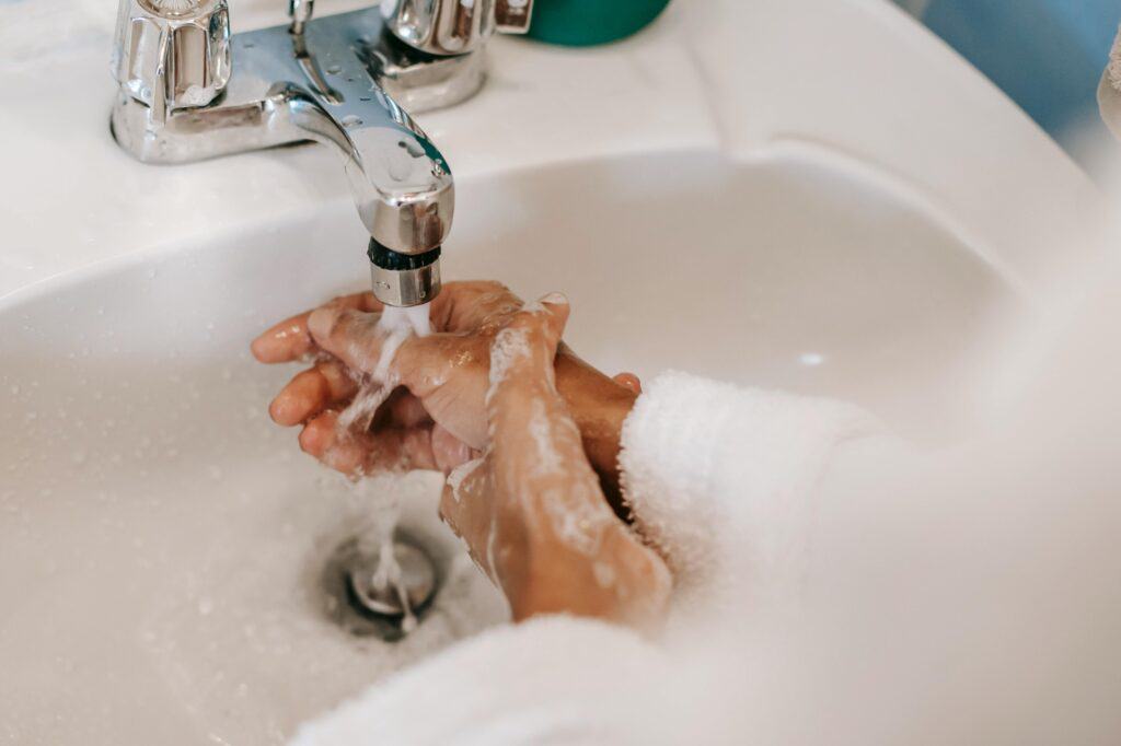 A woman is washing her hands by the sink
