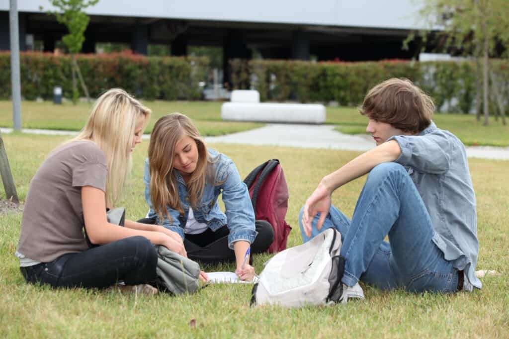Three students studying while sitting on the lawn