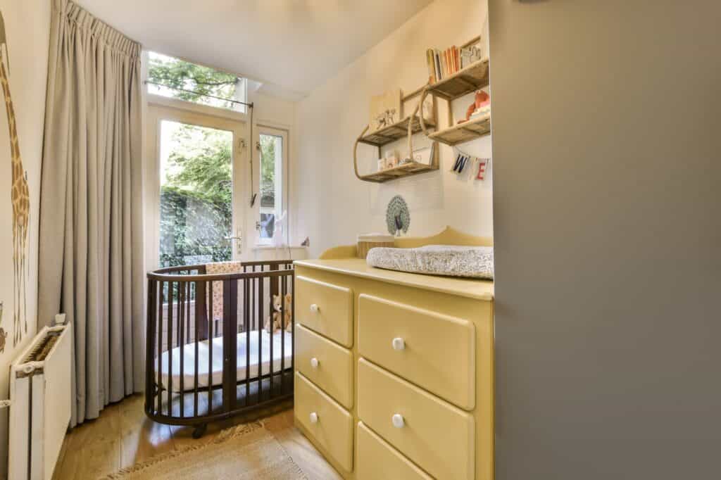A nursery with a crib and a yellow dresser