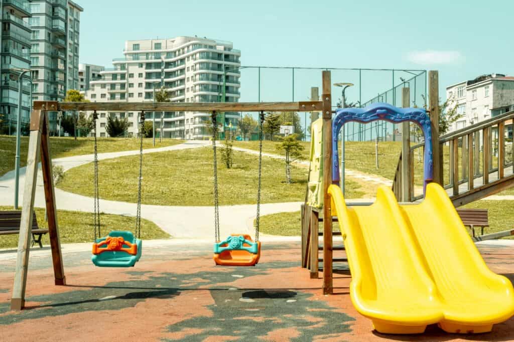 Children's playground with a basketball court and residential building in the background