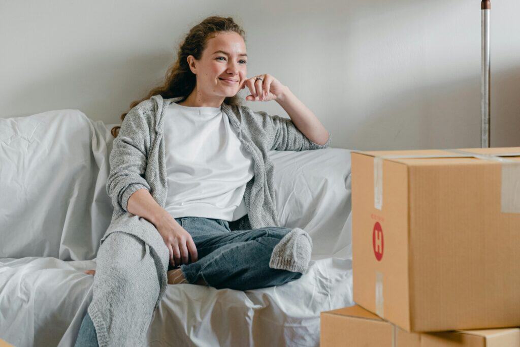 A smiling woman sitting on a couch after the move in the concept of stress-free experience