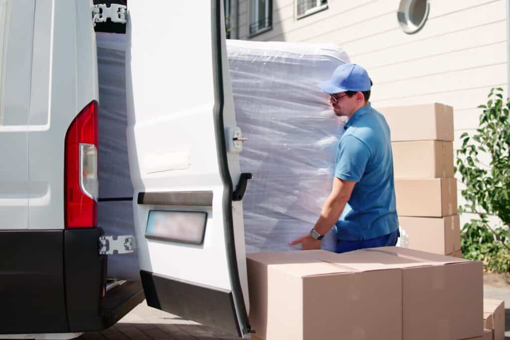 A mover at the back of the van loading a mattress